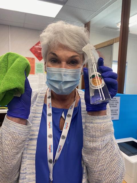 elderly woman in a mask holding a spray bottle