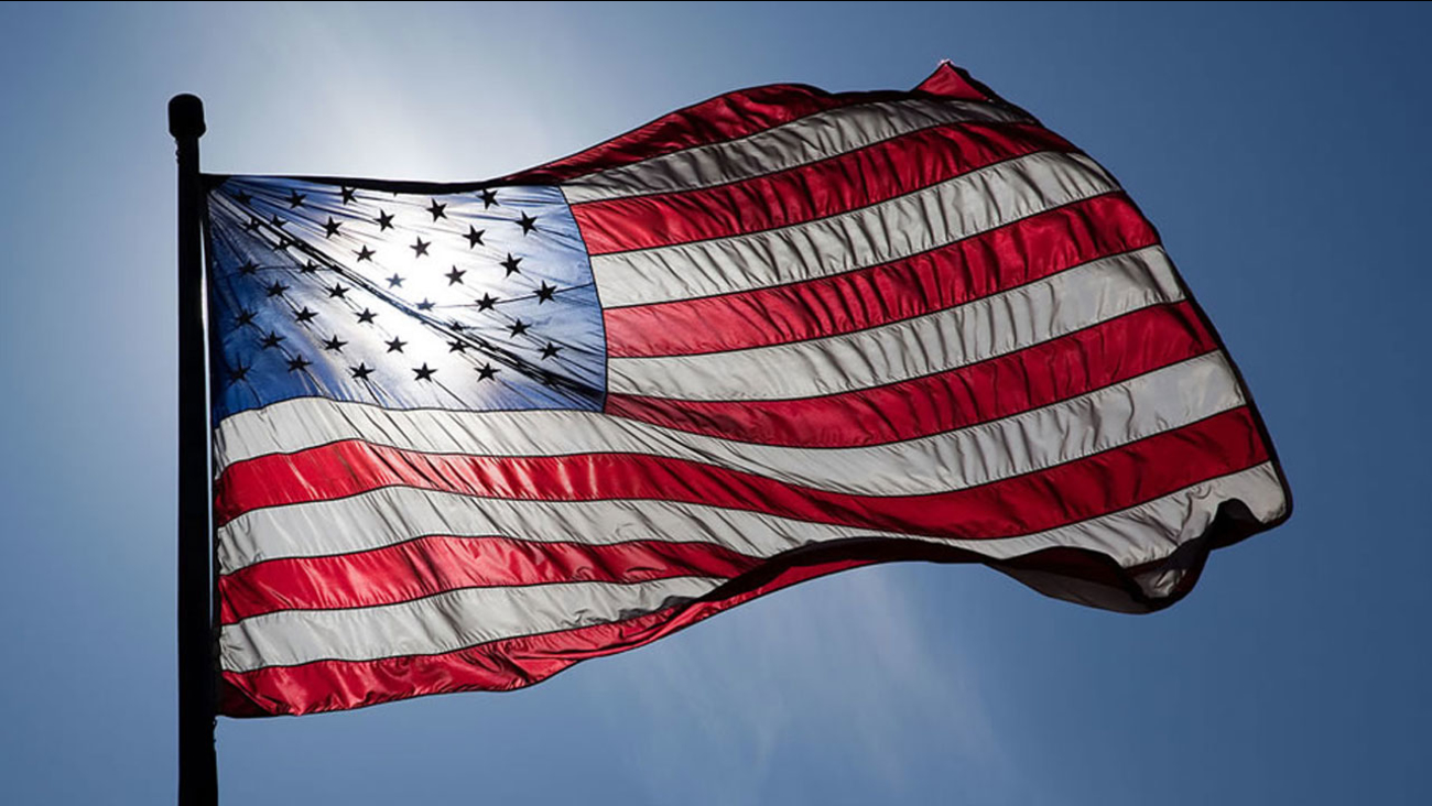 The american flag waving in the wind with the sun shining through the fabric.