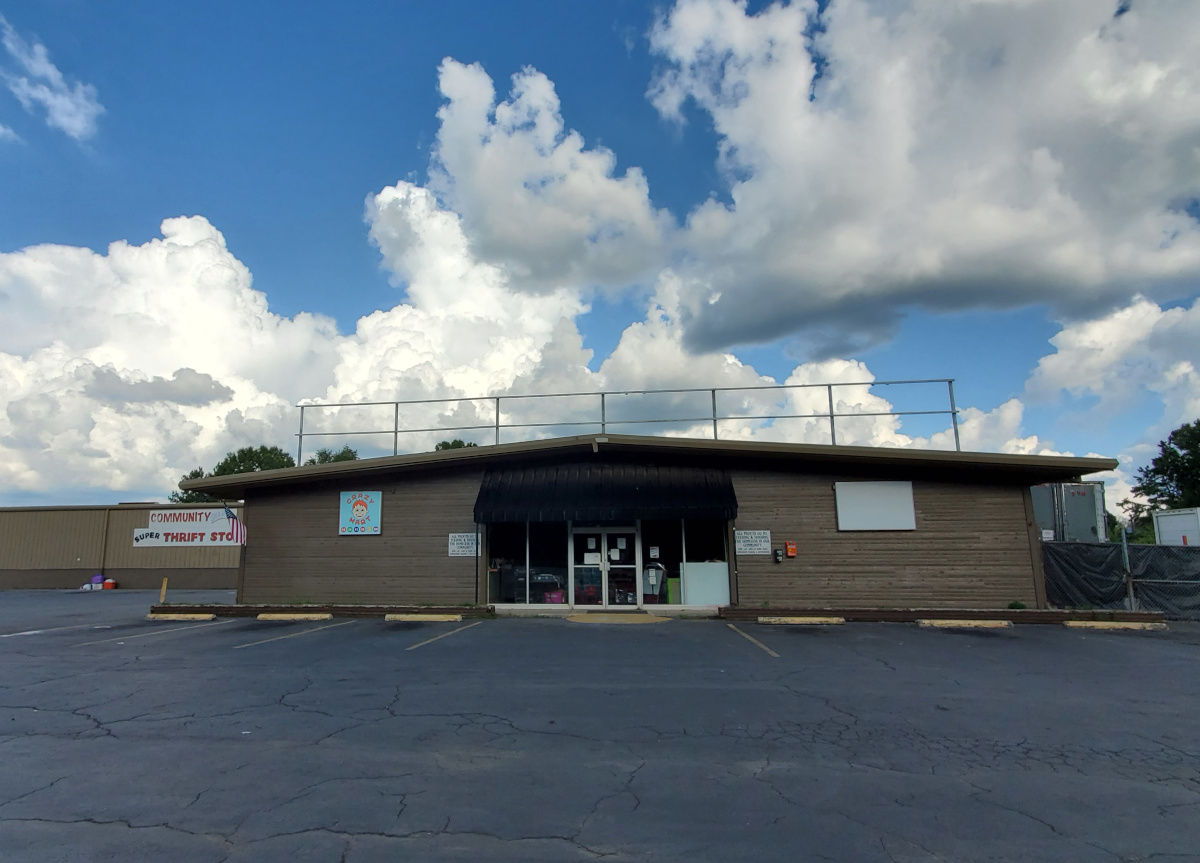 Front of a brown metal building and asphalt parking lot