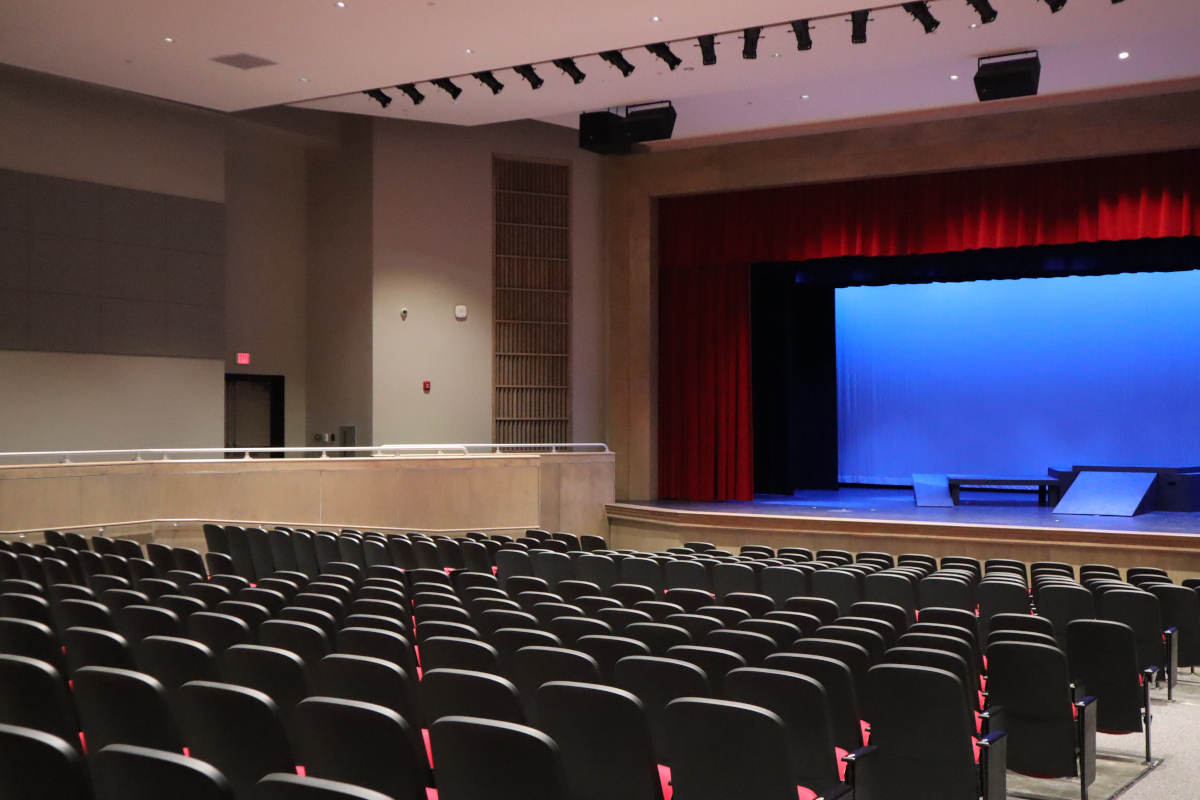 auditorium with red seats and drapes, blue lighting and a row of theater lights