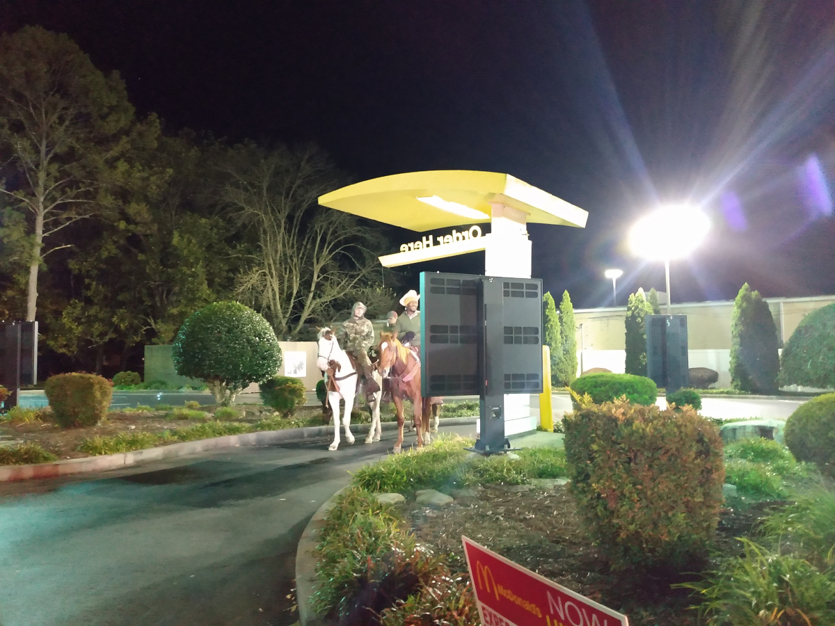 Three men on horses at a order screen for McDonalds